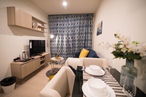 A modern living room with a sofa, coffee table, and dining table set for a meal. - Apartment BTS On Nut, Convenience Store Nearby - bkmono3 (Bangkok)