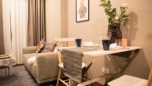 A living room with a sofa, a dining table, and a coffee table. There is a vase with flowers on the table. - Community Apartment - bkbhce12 (Bangkok)