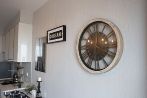 A kitchen with a clock, a sign that says "DREAM", and a framed picture on the wall. - Community Apartment - bkbhce49 (Bangkok)