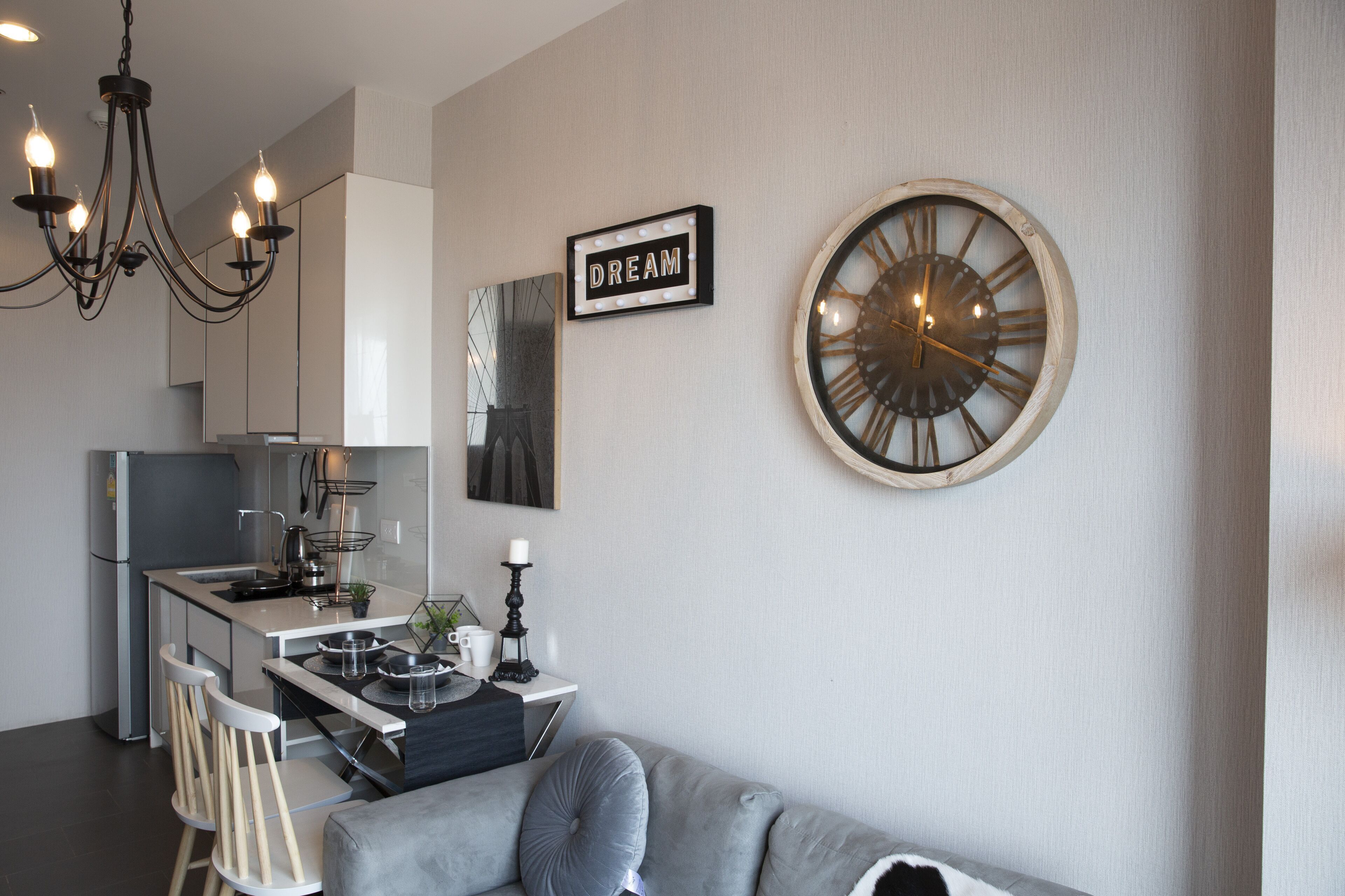 A modern kitchen with a dining area, a chandelier, a clock, and a sign that reads "DREAM".