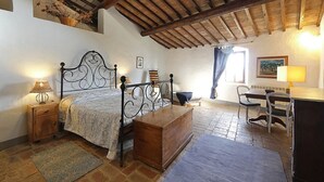 Un dormitorio con una cama de madera, una mesita de noche, un escritorio con silla y una ventana con cortinas.