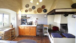 Una cocina rústica con armarios de madera, estufa a gas, cafetera y un colgador para ollas.