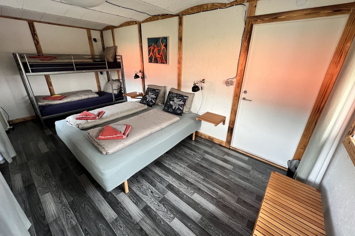 Une chambre avec un lit superposé, un lit simple et une petite table.