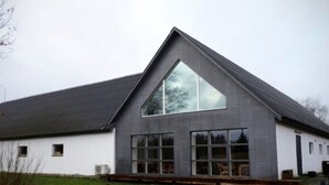 A modern building with a sloped roof, large windows, and a white exterior.