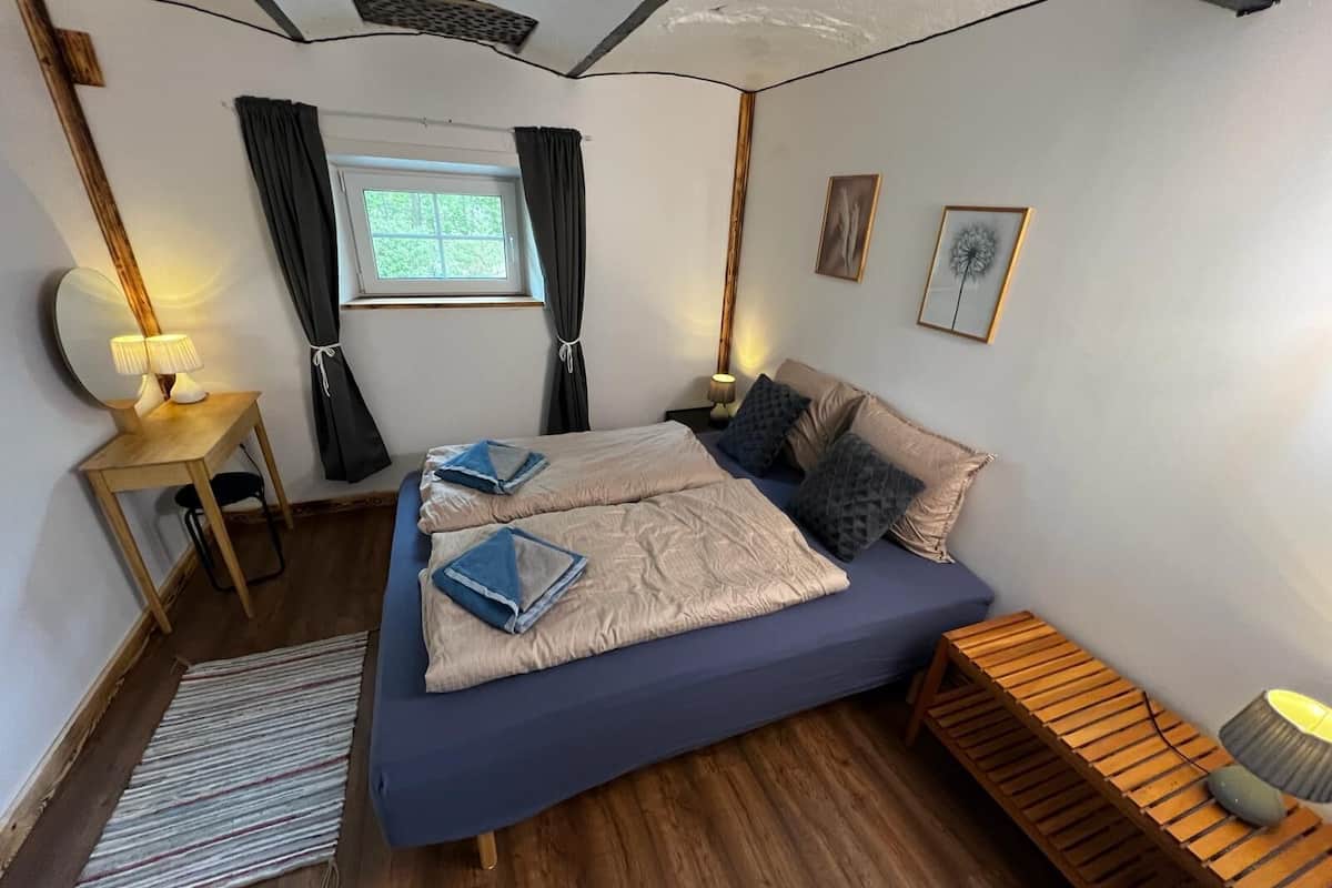 Une chambre à coucher avec un lit, des tables de chevet, une fenêtre et une vue sur l’extérieur.