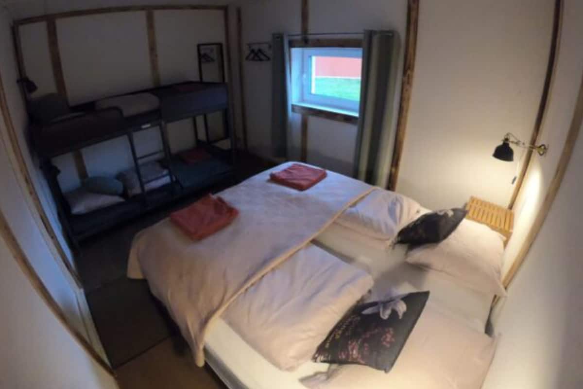 Une chambre de type dortoir, avec des lits superposés et un lit simple.