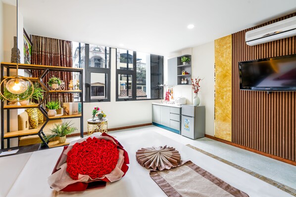 A modern living room with a large window, a flat-screen TV, a wooden wall panel, and a decorative rug. - Apro Aparthotel Saigon Center (Ho Chi Minh City)
