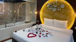 A hotel room with a large bed, a round wall decoration, a bathtub, and a mirror. - Apro Aparthotel Saigon Center (Ho Chi Minh City)