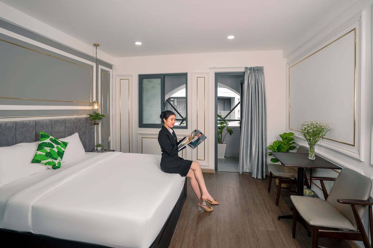 A hotel room with a large bed, a dining table, and a small seating area.