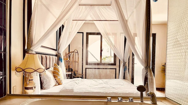 A bedroom with a large bathtub, a bed with white linens, and a canopy over the bed. - Apro Aparthotel Saigon Center (Ho Chi Minh City)