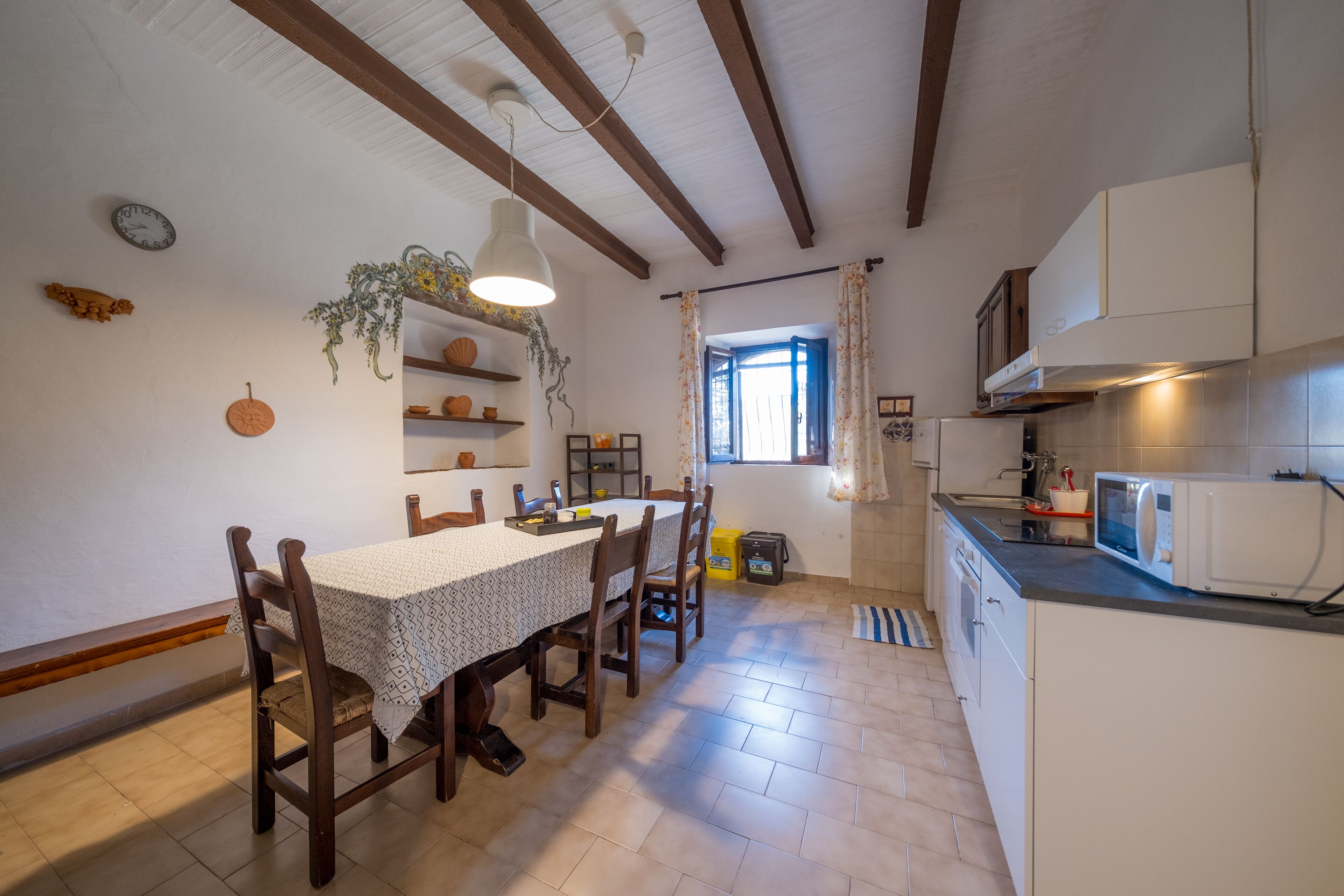 A kitchen with wooden chairs, a dining table, and a hanging plant.