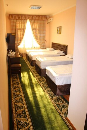 A hotel room with three beds, a desk, and a patterned carpet. - Grand Mumtoz Hotel (Tashkent)