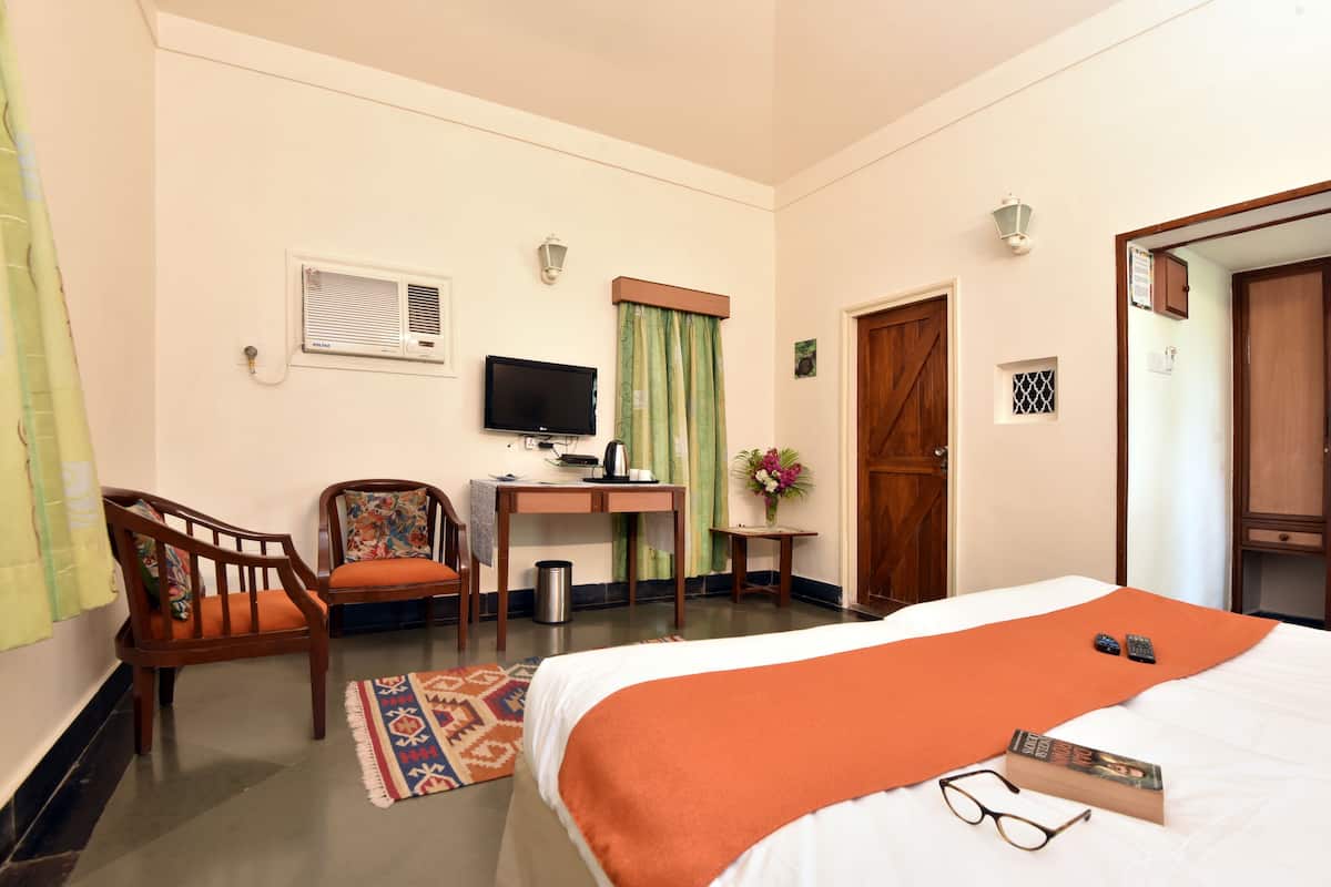 Ein Hotelzimmer mit Bett, Schreibtisch, Stuhl, Fernseher und einem kleinen Tisch mit Blumen.
