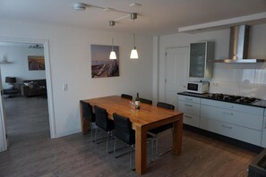 Una cocina moderna con armarios blancos, una campana extractora de acero inoxidable y un microondas.