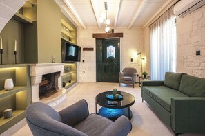 A modern living room with a fireplace, a television, and a green sofa. - Sea View Villa with Private Pool | West Crete (Kissamos)