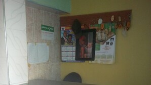 A reception desk with a bulletin board displaying various notices and a calendar. - Palin Hotel (Mwingi)