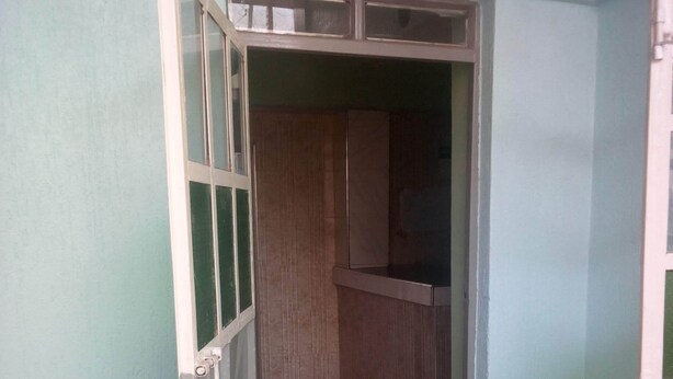 A room with a tiled floor, a wardrobe, and a door leading to another room. - Palin Hotel (Mwingi)
