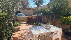 A patio with a glass table and white chairs, surrounded by potted plants and a tiled floor. - House for rent 50 m from the beach (Le Barcar ès)