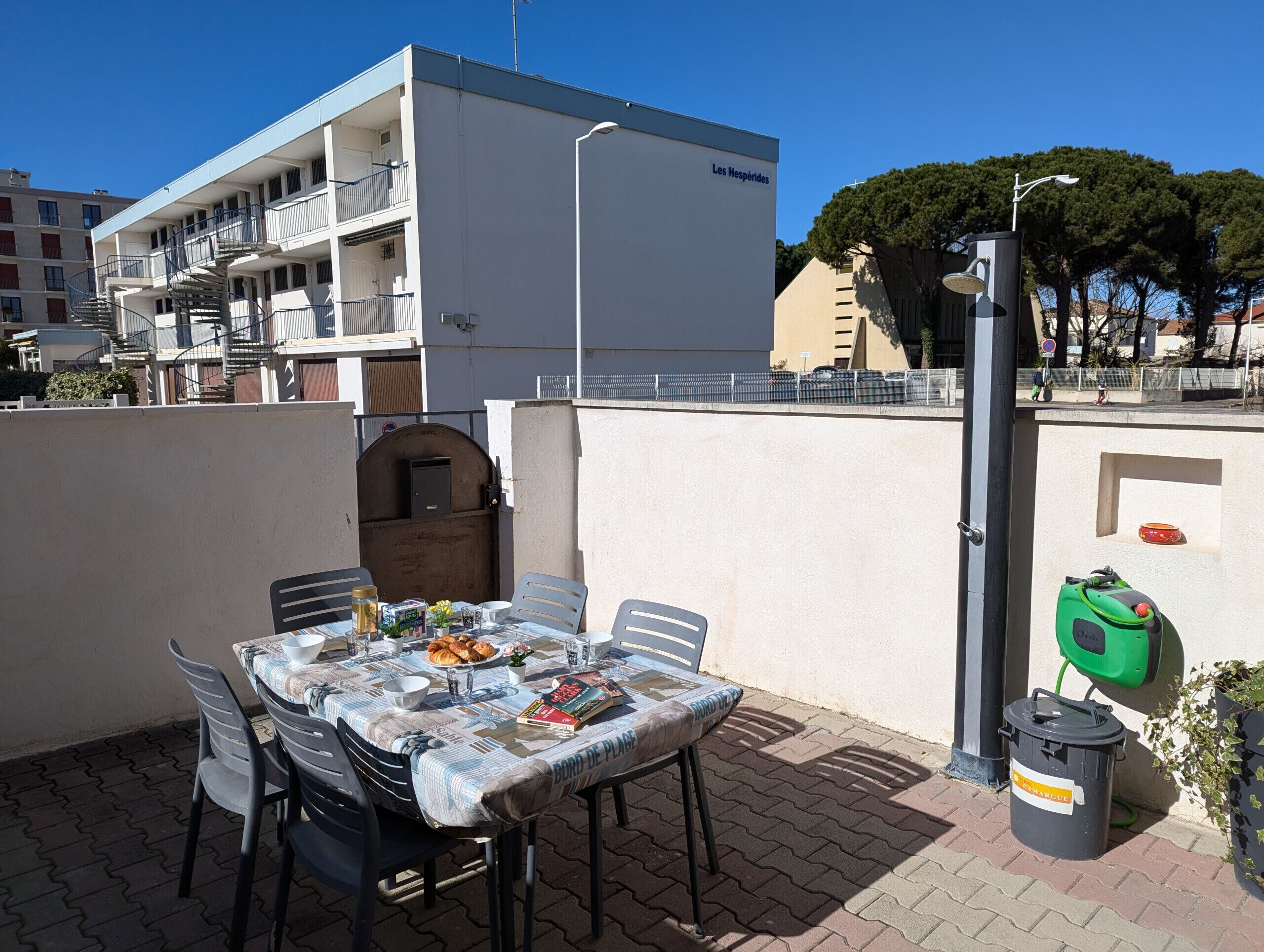 An outdoor patio with a table set for dining, surrounded by chairs.