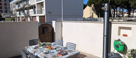An outdoor patio with a table set for dining, surrounded by chairs.