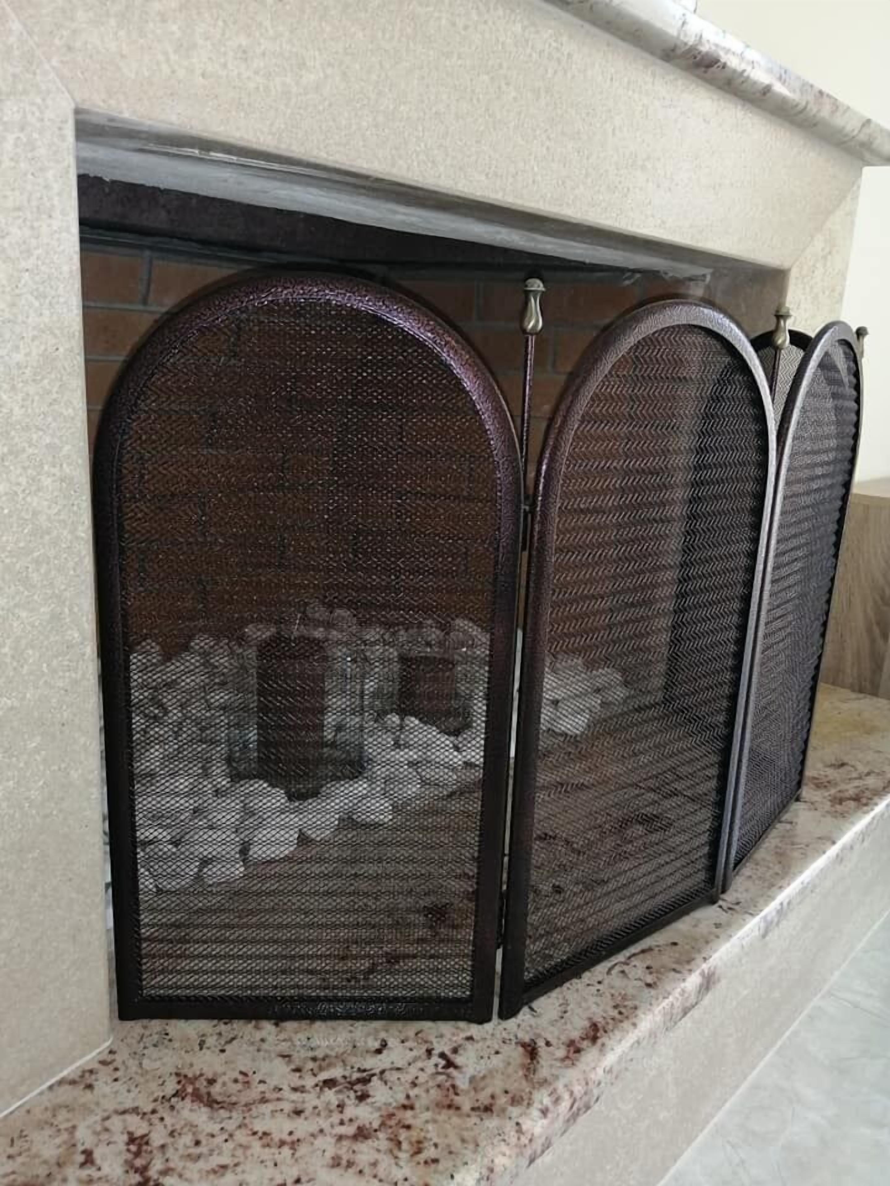 A fireplace with a metal screen and a stone surround.
