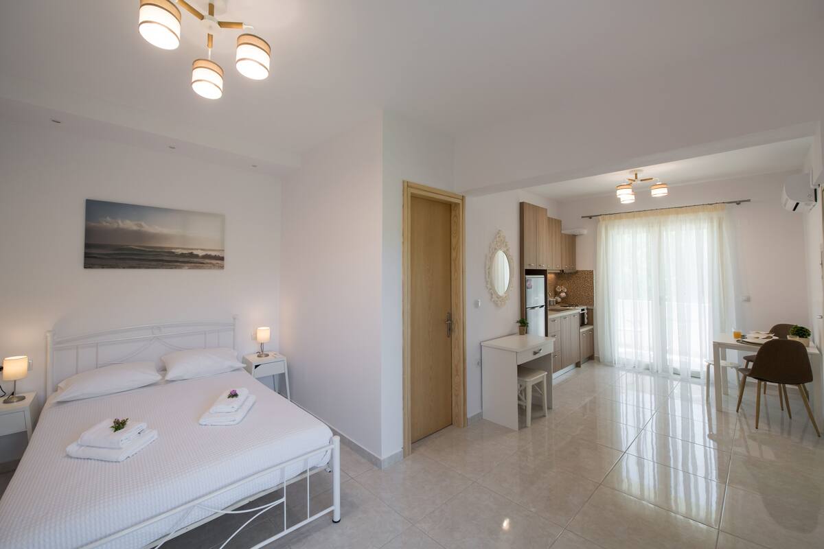 Quarto de hotel moderno com uma cama bem arrumada, uma pequena escrivaninha e um espaço de refeições.