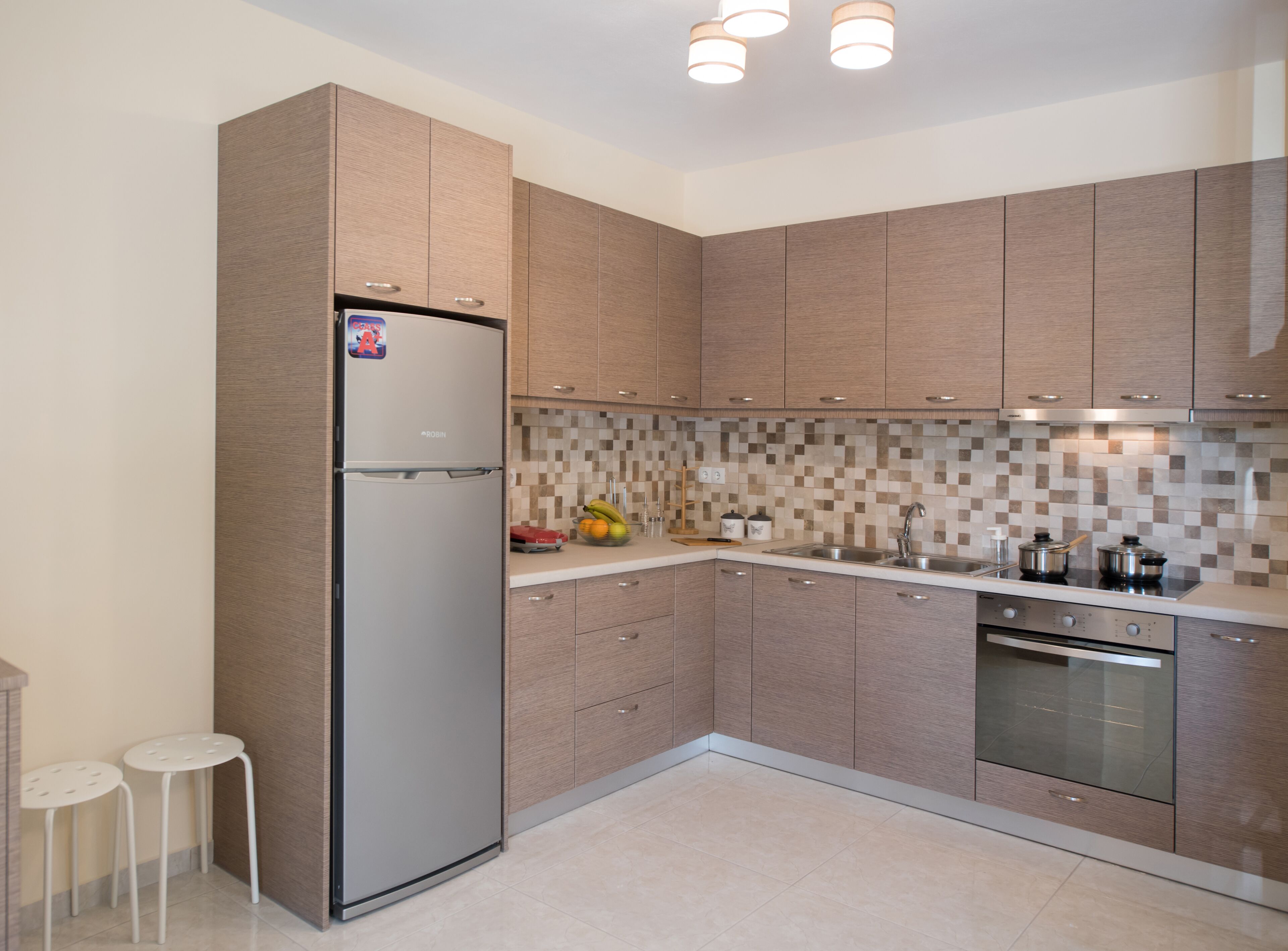 Una cocina moderna con armarios de madera, un refrigerador de acero inoxidable, salpicadero de azulejos y horno empotrado.