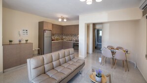 A modern living room with a sofa, a dining area with chairs and a table, a kitchen with cabinets and appliances, and a ceiling with recessed lighting. - Bounatsa Studios & Apartments (Lefkada)