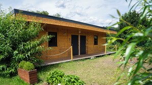 A wooden cabin with a porch, surrounded by greenery. - Camp Děčín (Decin)