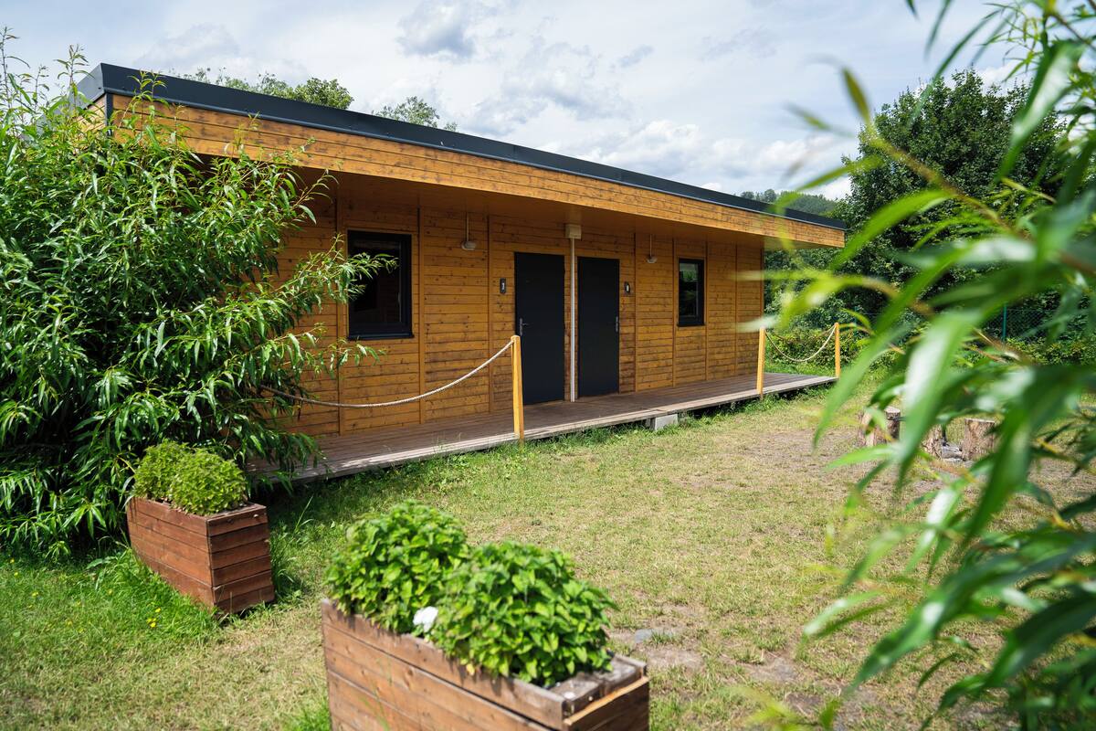 Eine Holzhütte mit Veranda, umgeben von viel Grün.