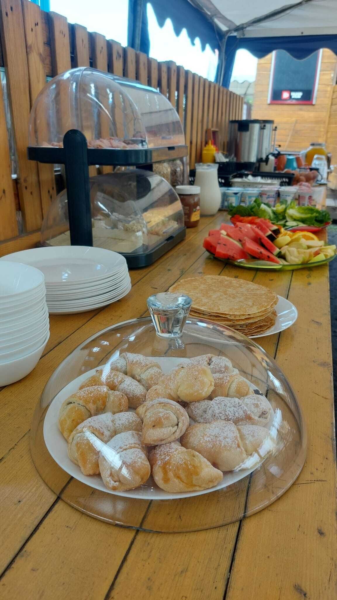 A buffet table with a variety of food items including pastries, fruits, and condiments.
