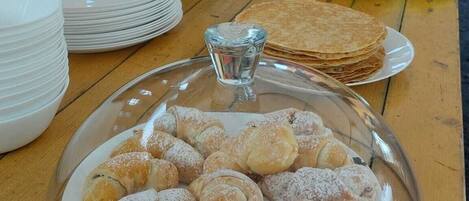 A buffet table with a variety of food items including pastries, fruits, and condiments.