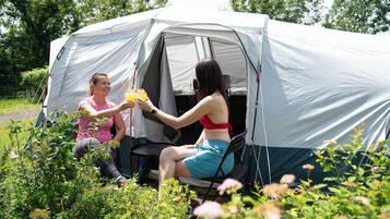 Two people sitting outside a tent in a natural setting.