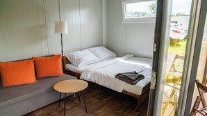 A room with a bed, a sofa, a small table, and a window. - Camp Děčín (Decin)