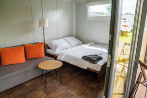 Una habitación con una cama, un sofá, una mesita y un ventanal.