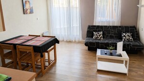 A living room with a dining table, chairs, a sofa, and a coffee table.