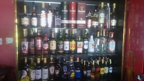 Um bar com vários tipos de bebidas alcoólicas, incluindo marcas como Glenfiddich e Jameson.