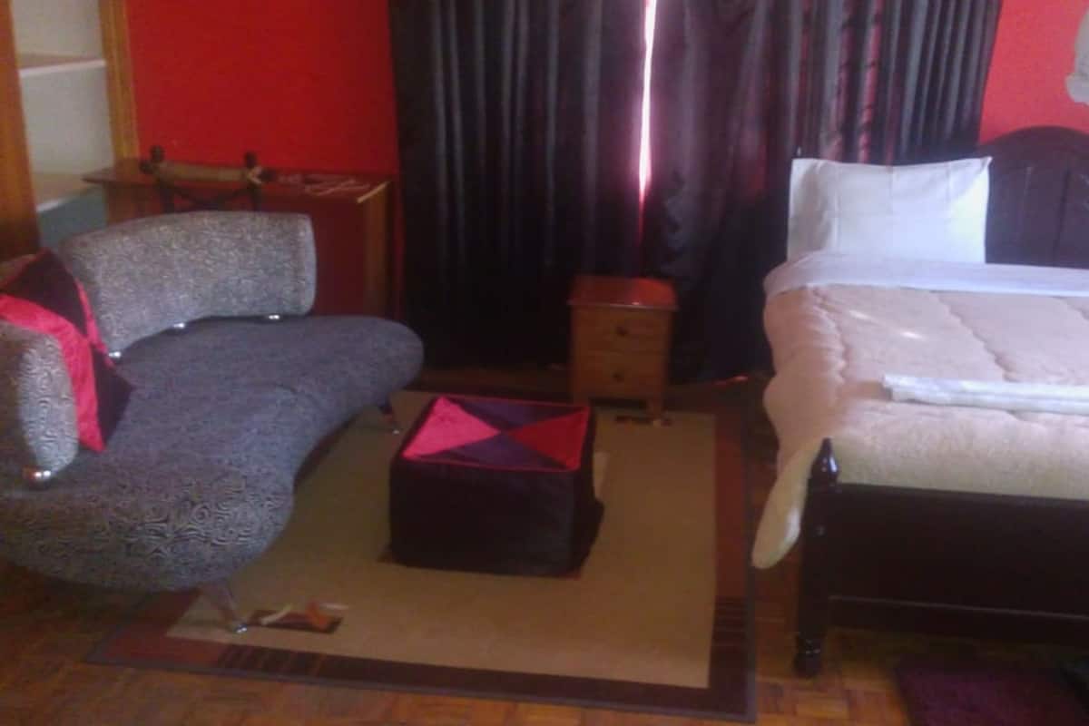 A room with a bed, a chair, a small table, and a nightstand.