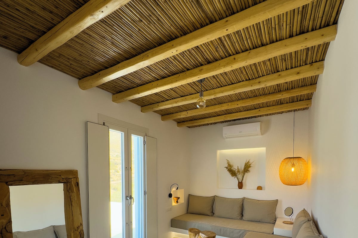 A modern living room with a wooden ceiling, a sofa, a coffee table, and a mirror.