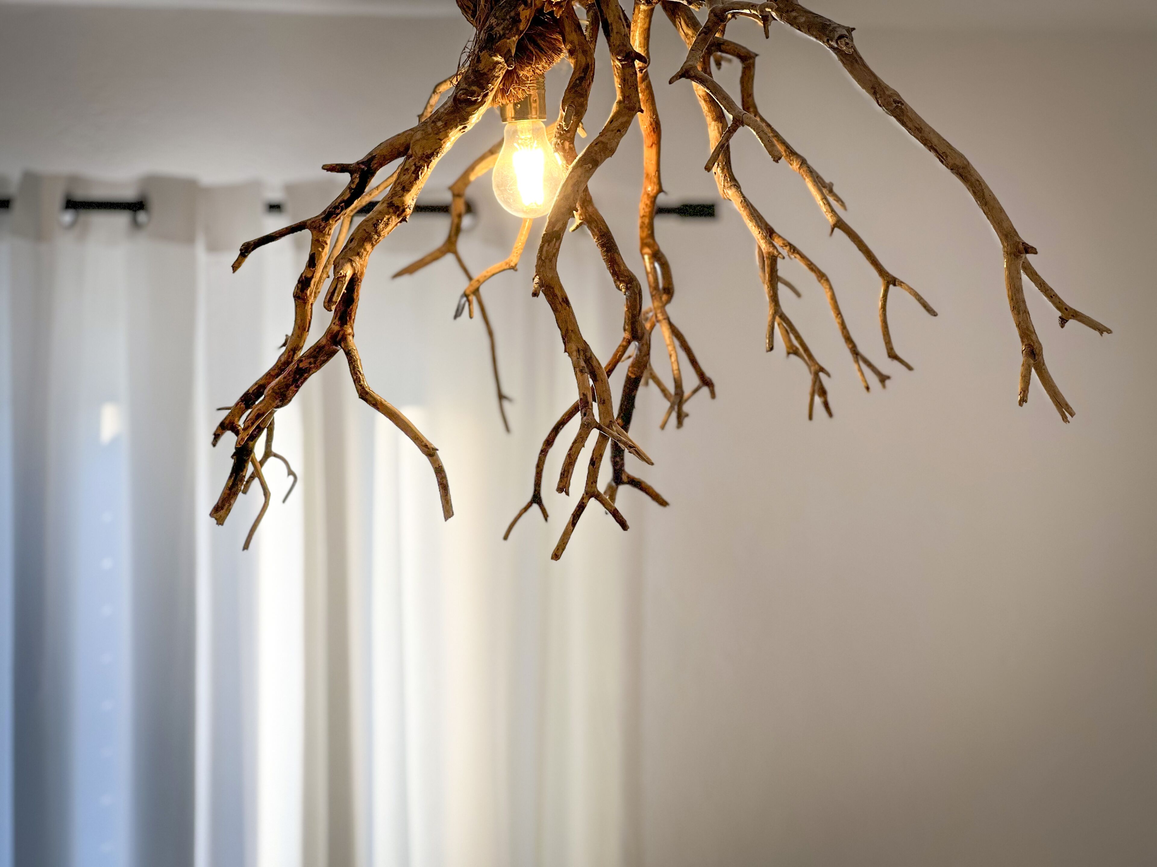 A chandelier with a unique design featuring branches and a light bulb.