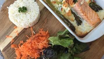 A meal consisting of rice, salmon, asparagus, and shredded carrots on a wooden board.