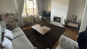 Una sala de estar con sofá, sillones, mesa de centro, chimenea y televisor.