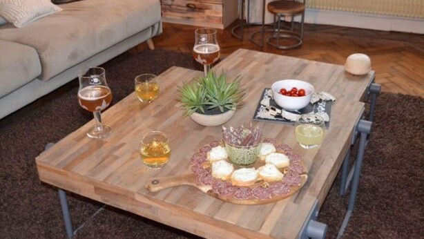 Una mesa de centro de madera con bebidas, aperitivos y una pequeña planta.