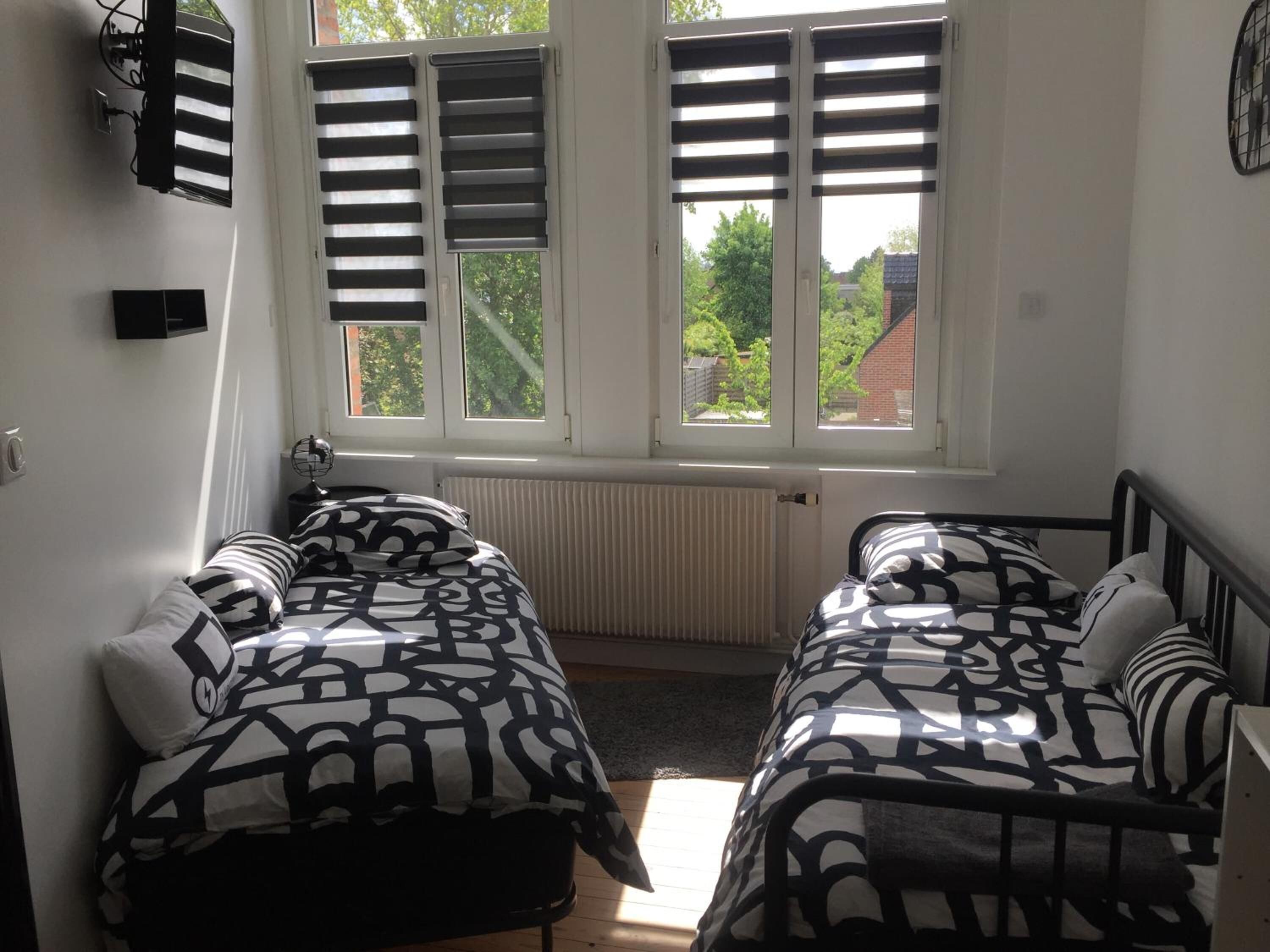 Un dormitorio con dos camas, un radiador y una ventana con contraventanas.