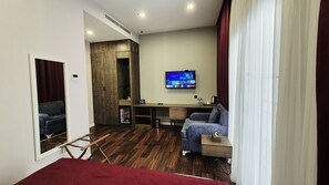 A hotel room with a bed, a desk, a television, and a seating area.