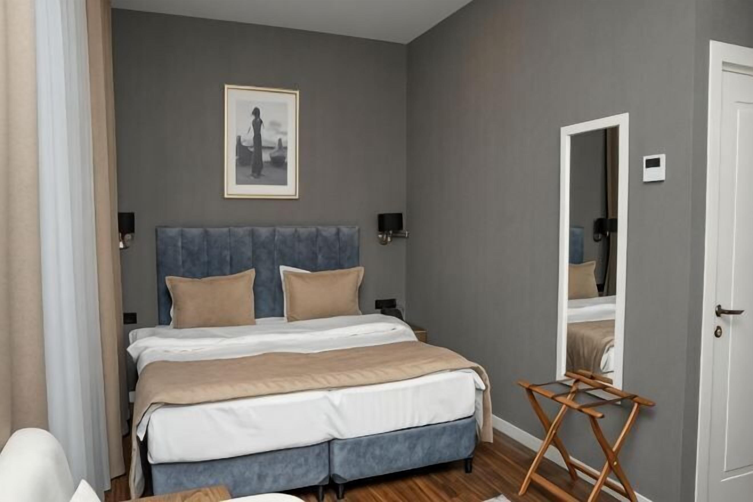 A bedroom with a bed, a mirror, a chair, and a wooden folding table.
