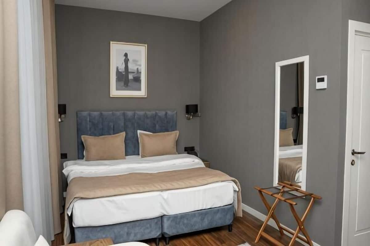 A bedroom with a bed, a mirror, a chair, and a wooden folding table.