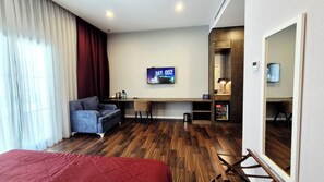 Een hotelkamer met een bed, een bureau, een stoel, een televisie en een spiegel.
