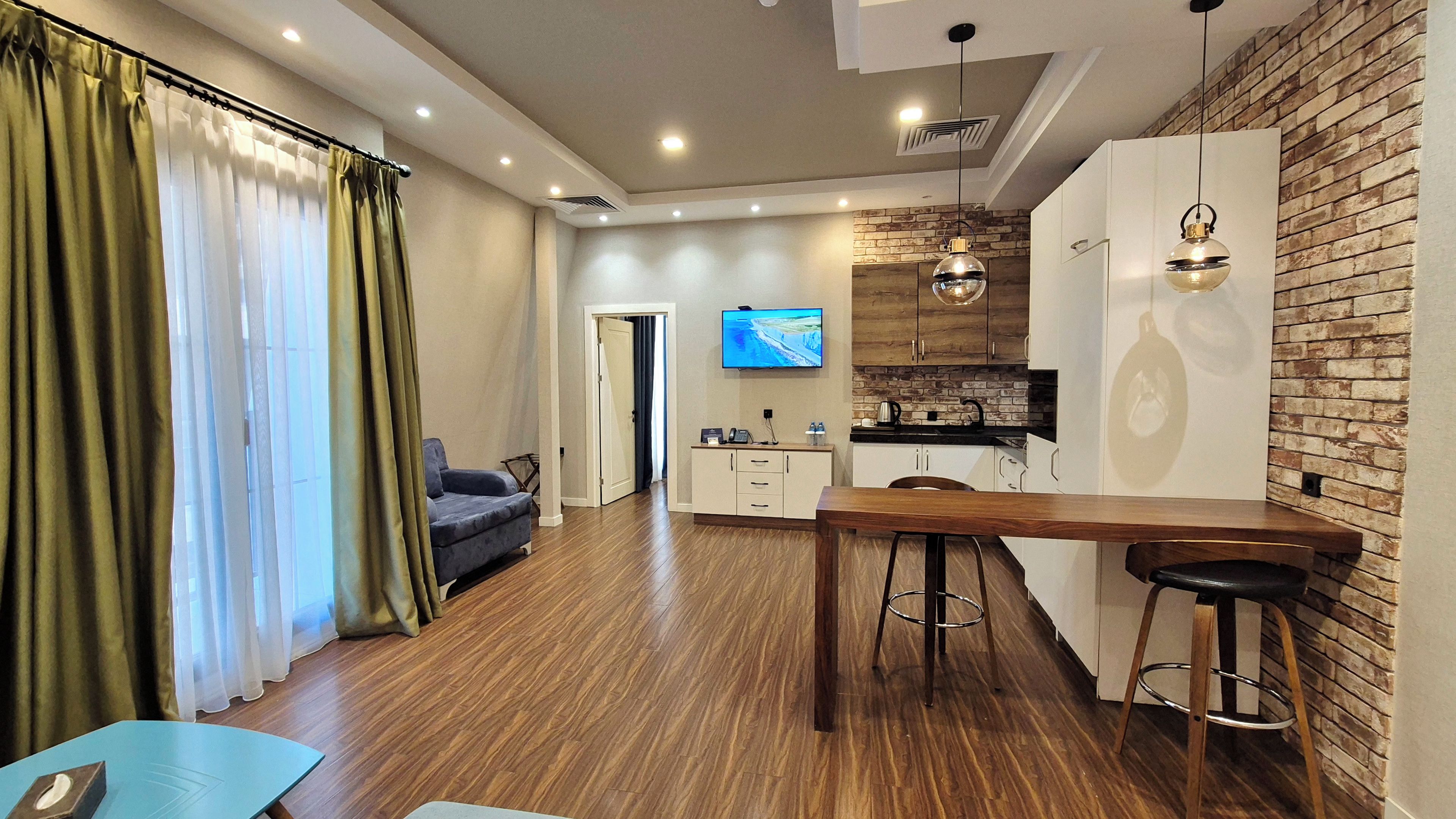 A modern living room with a sofa, a dining table, and a kitchen area with a TV.