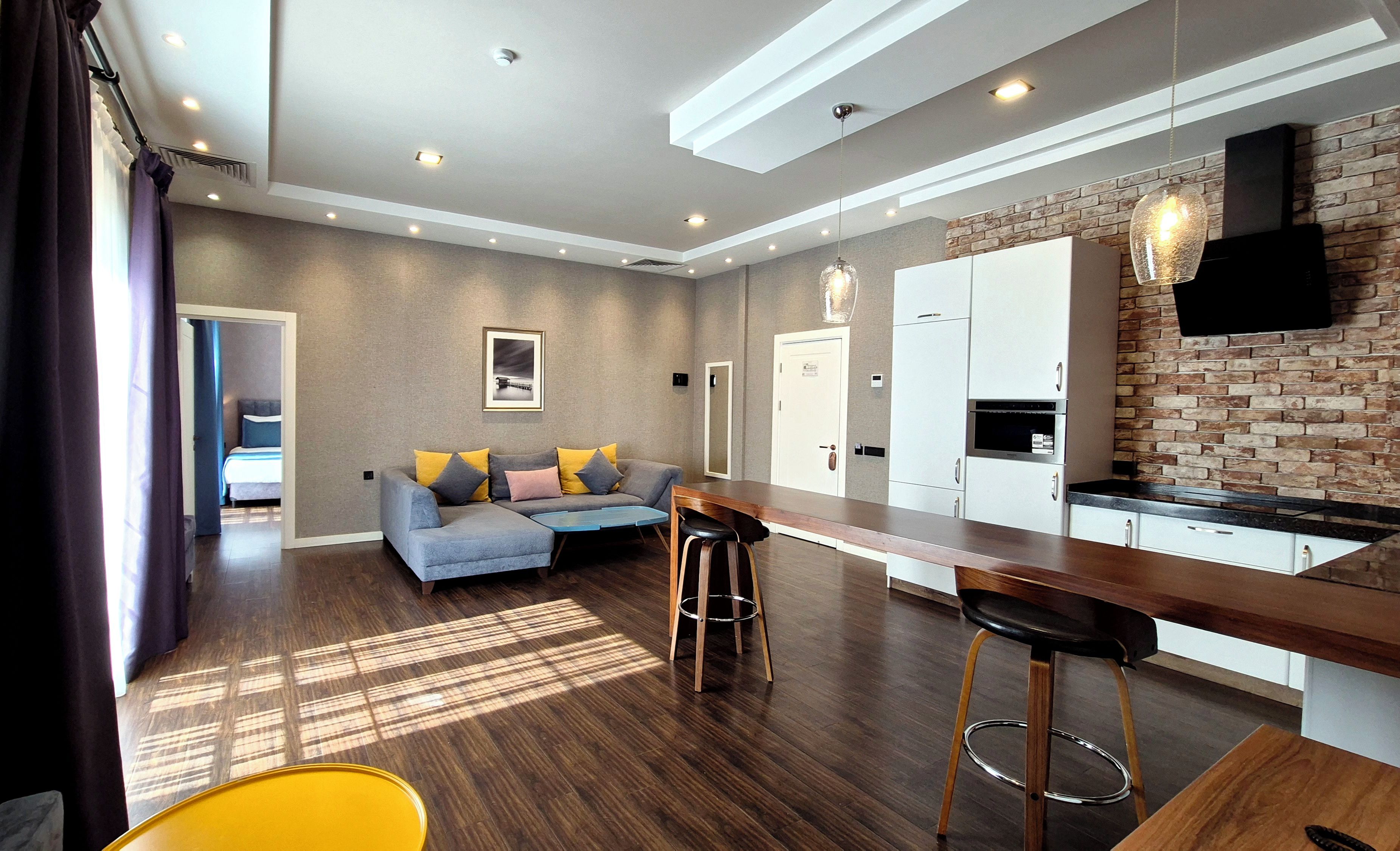 A modern kitchen with a brick wall, a bar area, and a seating space with a sofa and chairs.